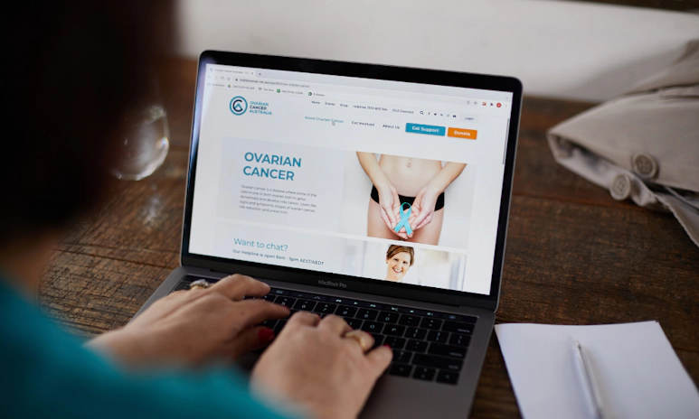 Woman on laptop, browsing the Ovarian Cancer Australia website.