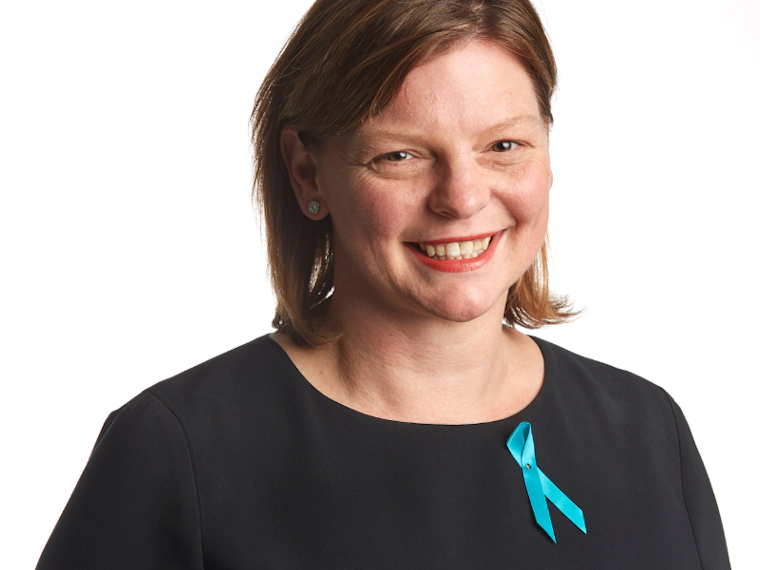 Woman in black top and teal ribbon smiling