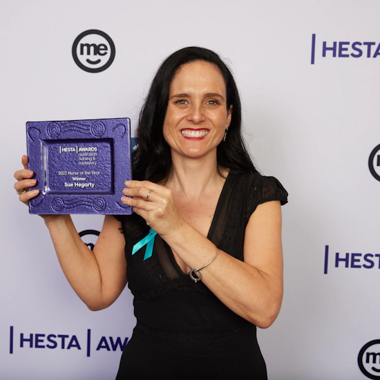 Woman in black dress holding up a purple award