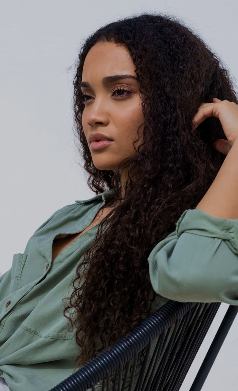 Woman sitting in a chair with her hand on her hair.