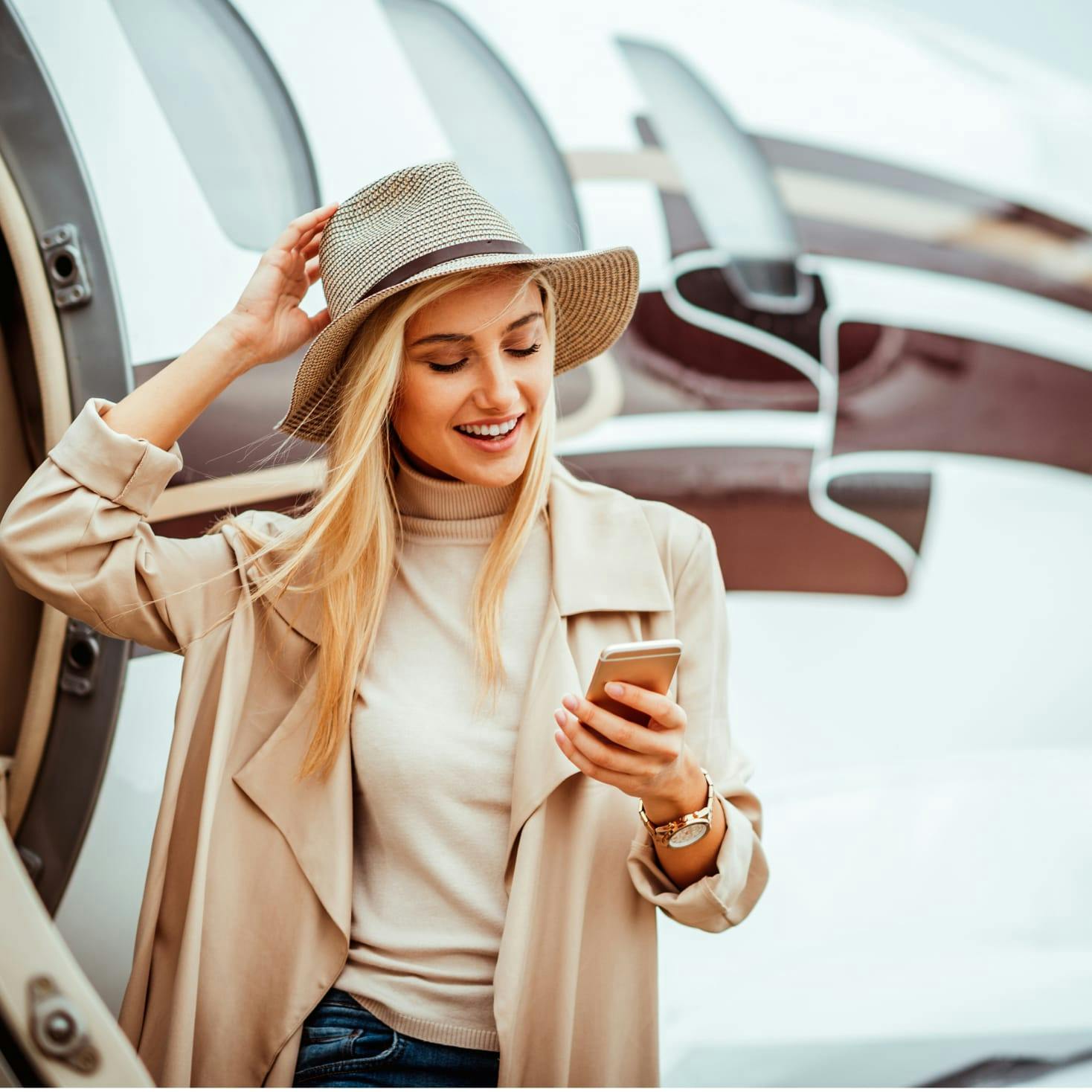 Woman looking at her phone and exiting a private plane.