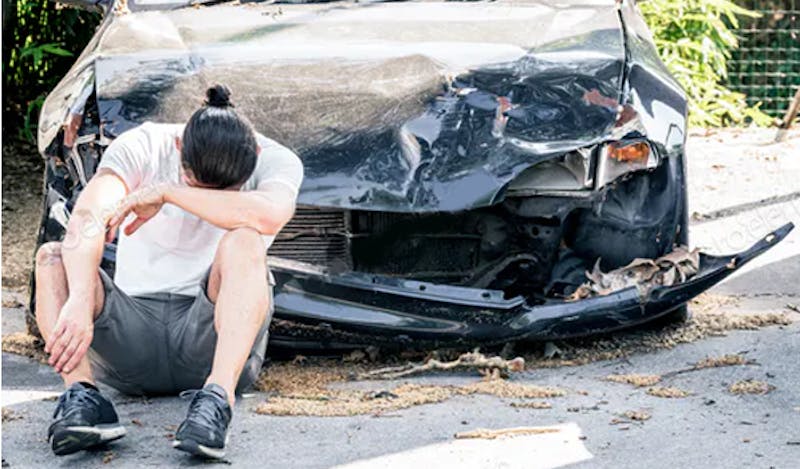 Distressed man next to crashed car