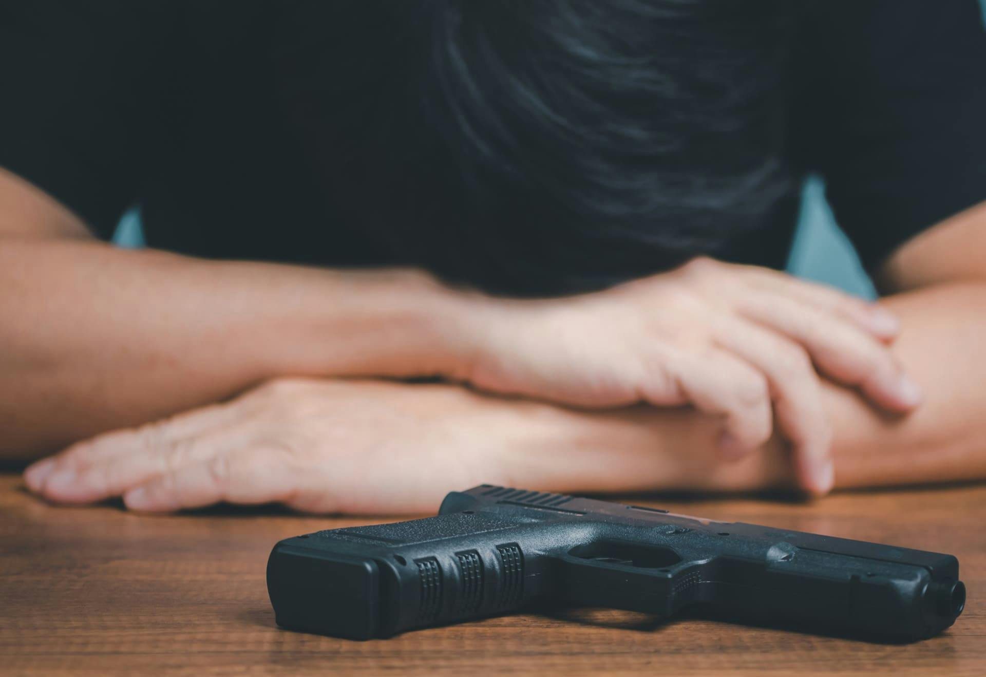 Man with his head down next to a gun