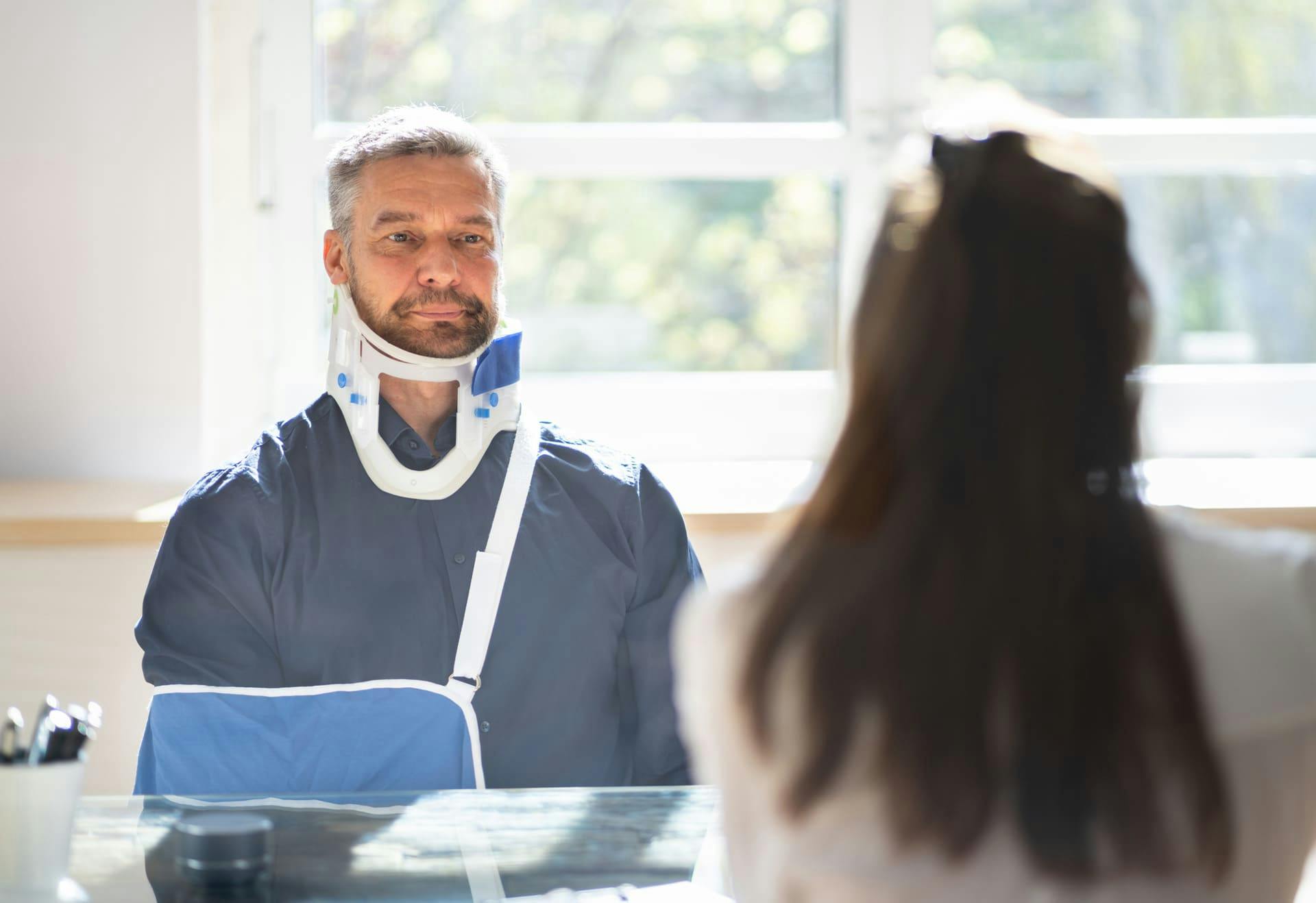 Man in a neck brace speaking with a medical person.