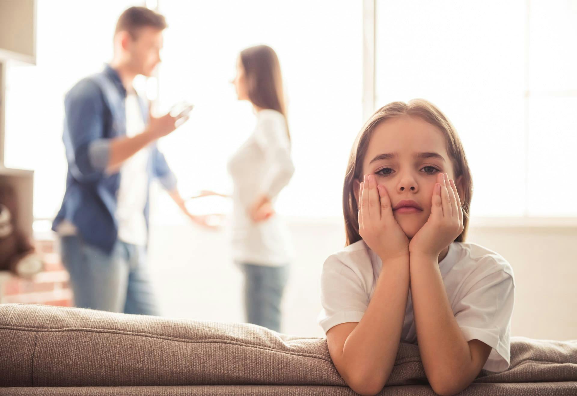 Upset child with parents arguing in the background