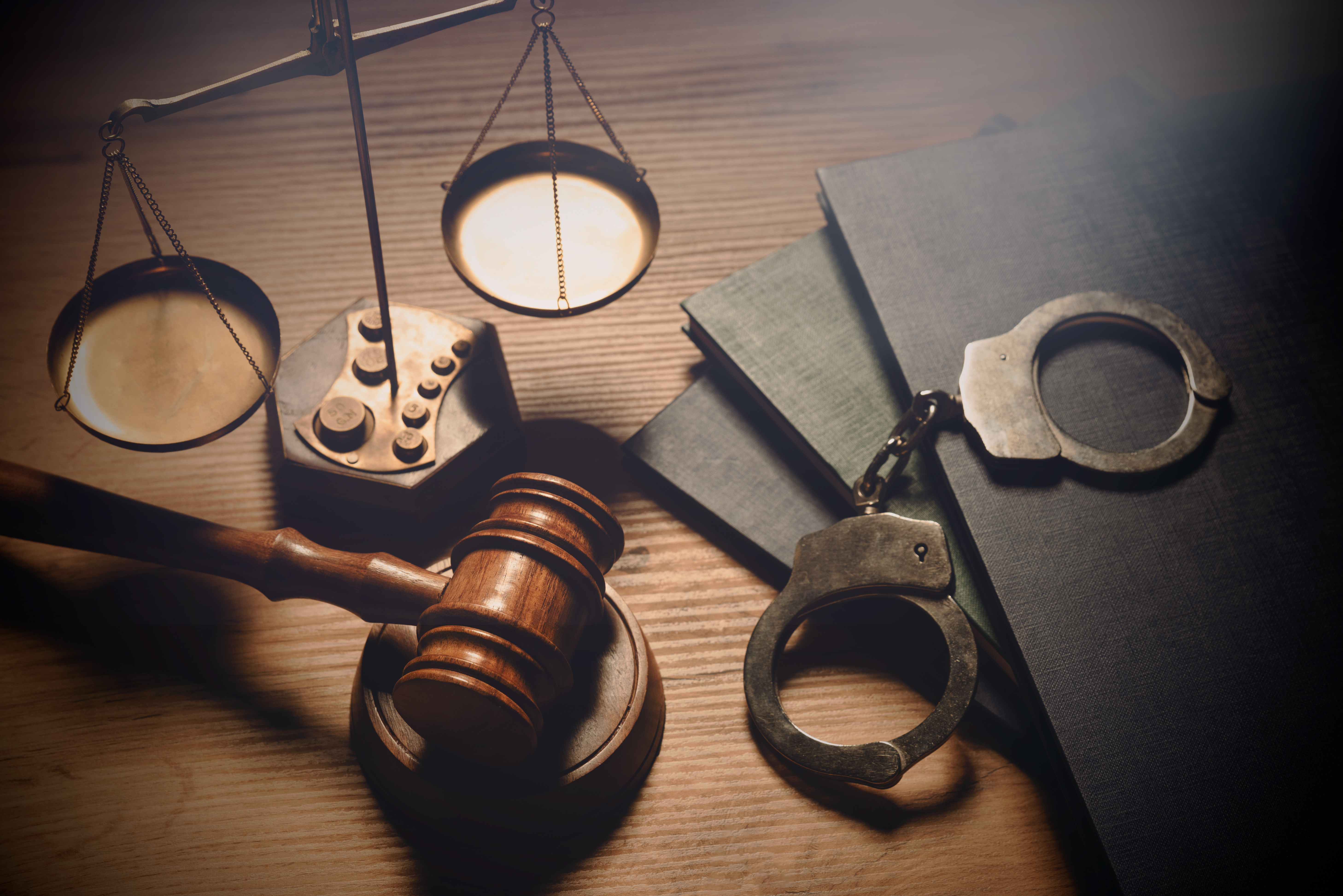 handcuffs, a gavel and scales of justice on a desk