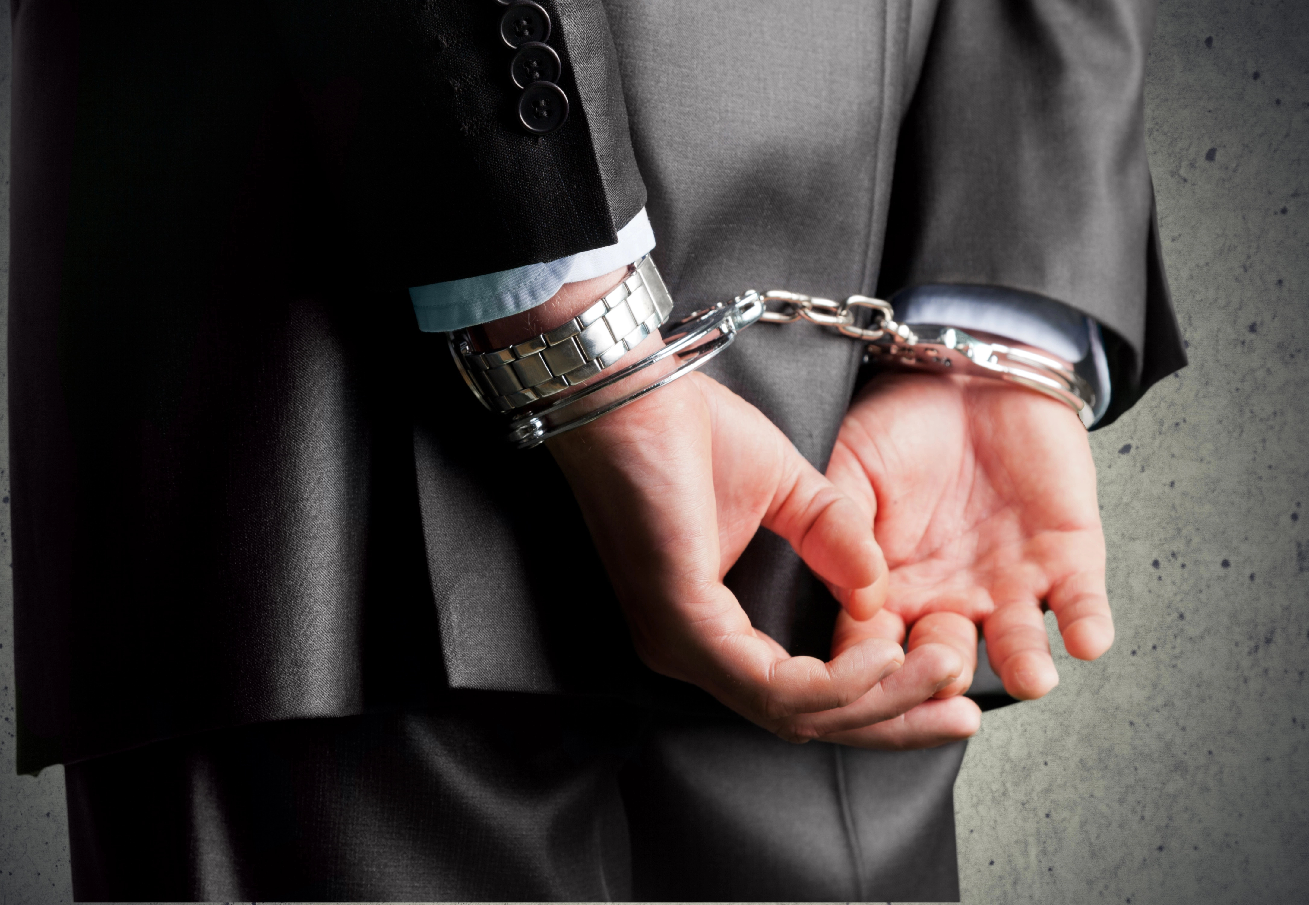 man's hands in handcuffs behind his back