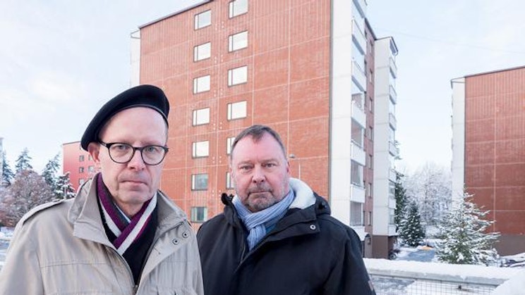 kaksi miestä seisoo vierekkäin rakennuksen edessä