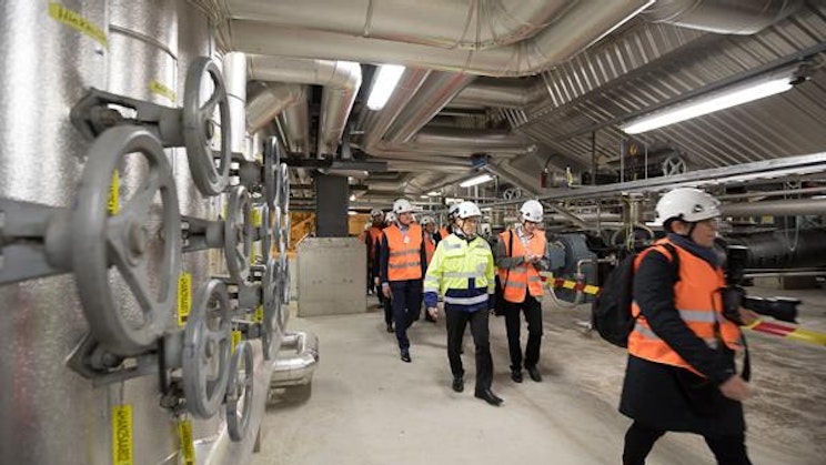 ryhmä ihmisiä oransseissa liiveissä ja kypärissä