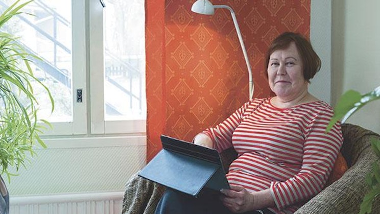 nainen on tuolilla pitelemässä kansiota