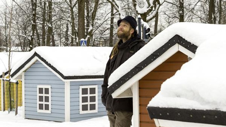 mies seisoo lumen peittämän talon edessä