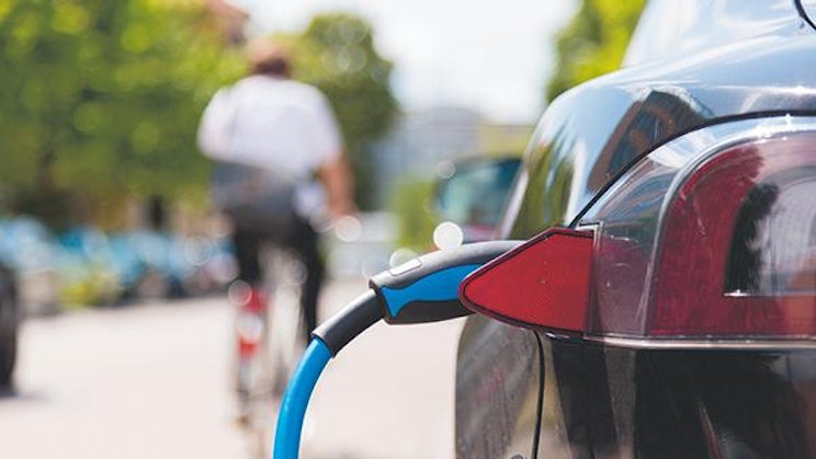 mies ajaa pyörällä kadulla auton vieressä