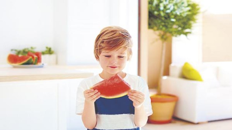 nuori poika pitelee palaa vesimelonia käsissään
