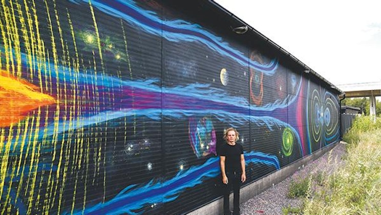 nainen seisoo värikkään seinän edessä