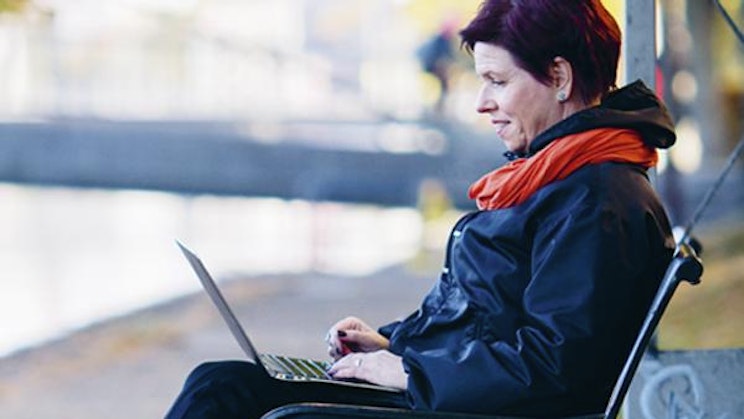 nainen on penkillä kannettavalla tietokoneella