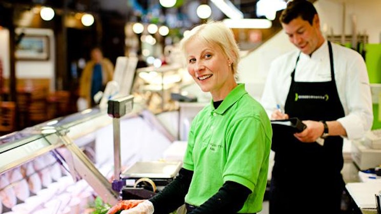 Herkkunuotan työntekijä käsittelee tuoretta kalaa Turun Kauppahallin kalatiskillä.