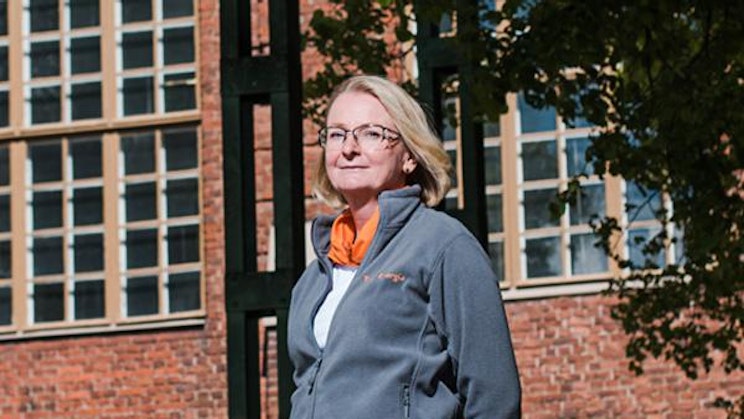 nainen seisoo tiilirakennuksen edessä