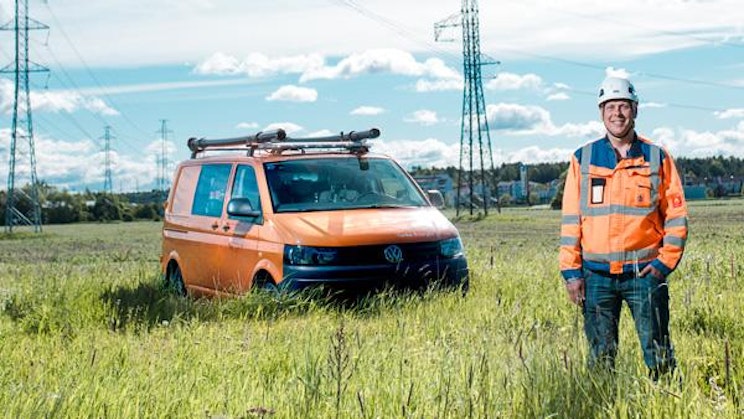 mies seisoo pakettiauton vieressä pellolla