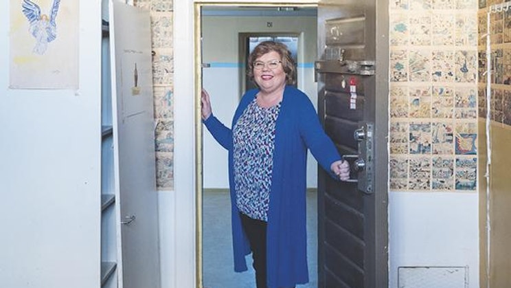 nainen seisoo rakennuksen ovella