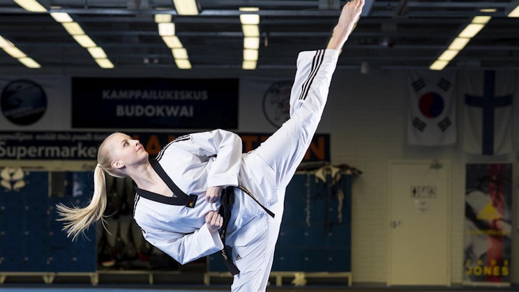 nainen valkoisessa karateasussa potkimassa