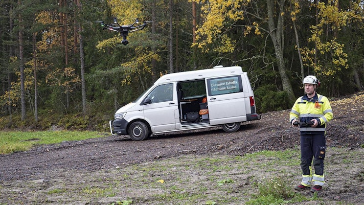 mies seisoo valkoisen pakettiauton vieressä hiekkatiellä