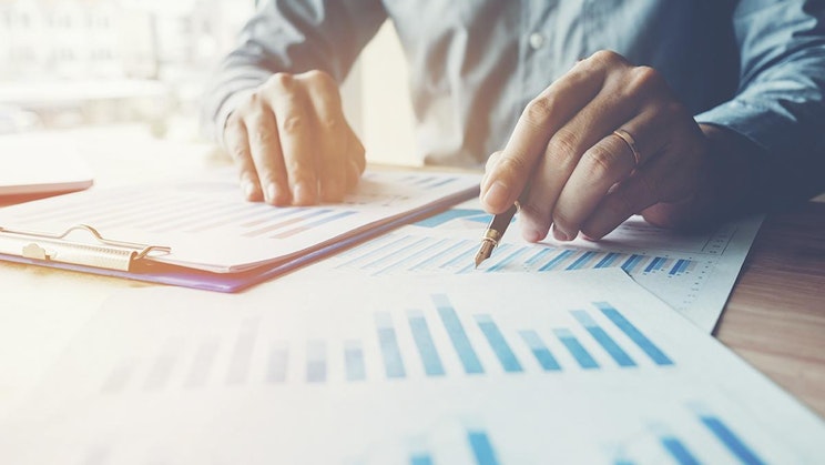 henkilö on pöydän ääressä kynän ja paperin kanssa