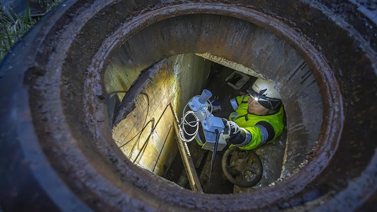 Teemu Mikkola kaivossa asentamassa kaukolämpökaivon valvonta-anturia.