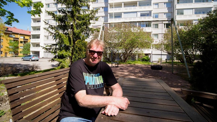 mies on puupenkillä rakennuksen edessä