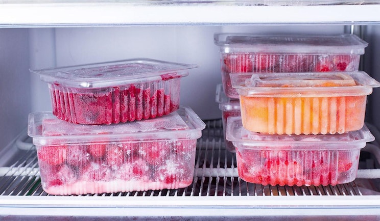jääkaappi, joka on täytetty hedelmillä täytetyillä muovisäiliöillä
