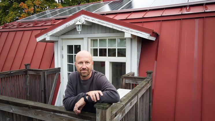 mies seisoo parvekkeella punaisen rakennuksen vieressä