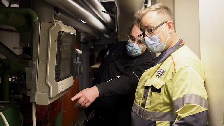 pari miestä seisoo vierekkäin koneen lähellä