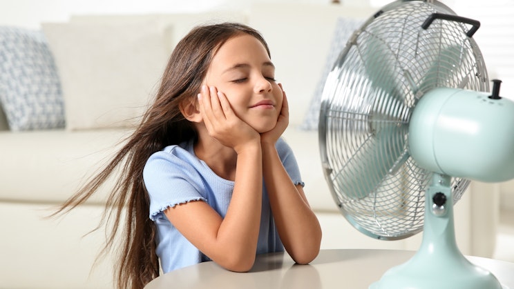 pieni tyttö on pöydässä tuulettimen vieressä