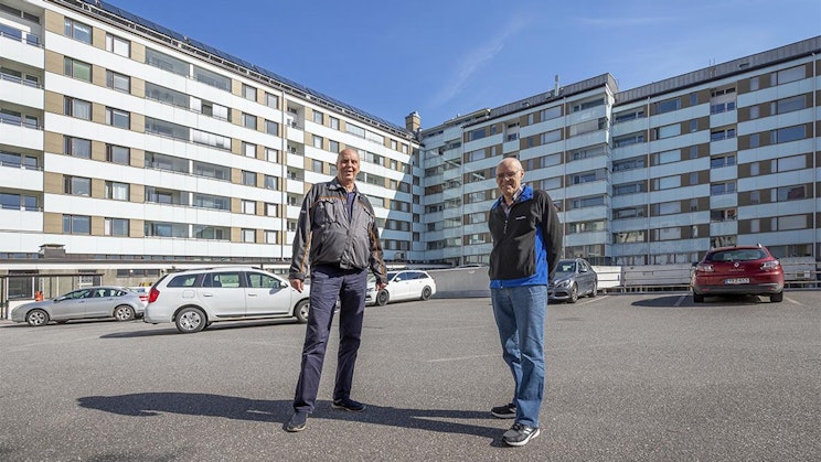 kaksi miestä seisovat parkkipaikalla