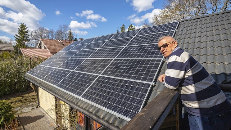 mies seisoo katon päällä aurinkopaneelin vieressä
