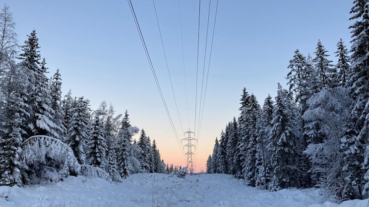 lumipeiteinen tie sähkölinjoineen kaukaa