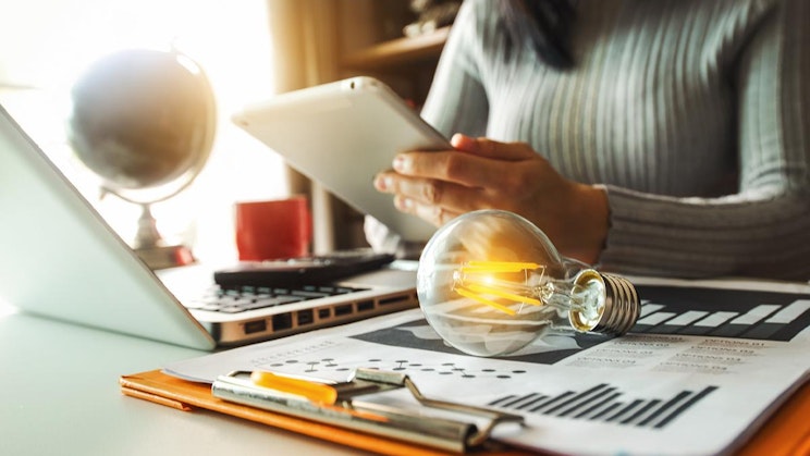 nainen on pöydän ääressä ja käyttää tablettia