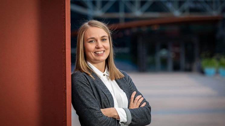 nainen nojaa seinää vasten kädet ristissä