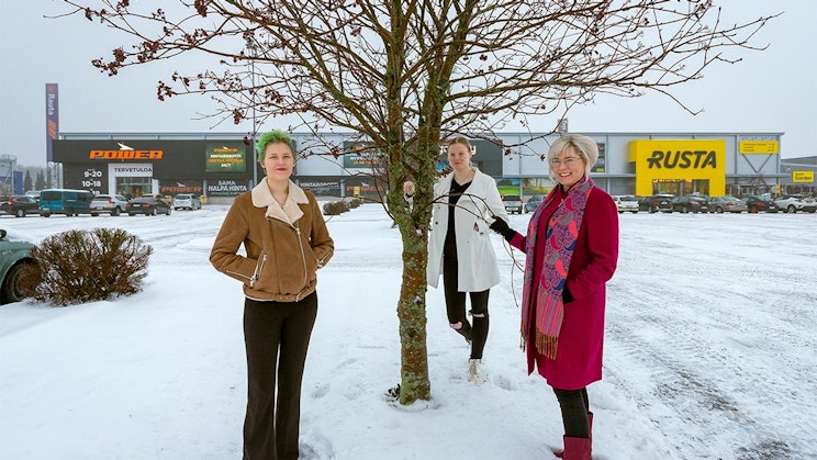 kolme naista seisomassa puun vieressä lumessa