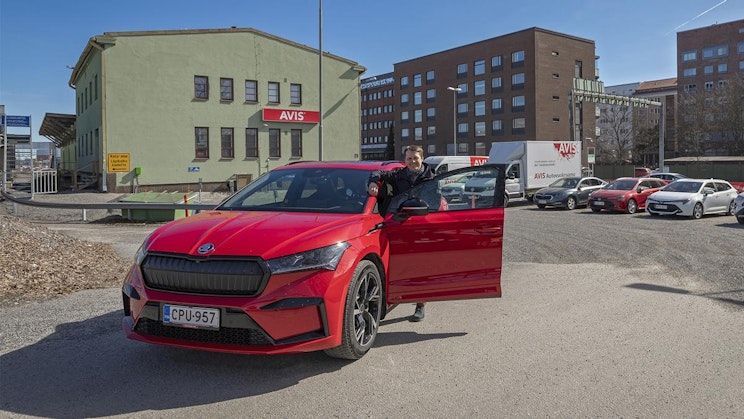 punainen auto pysäköitynä parkkipaikalle rakennuksen viereen
