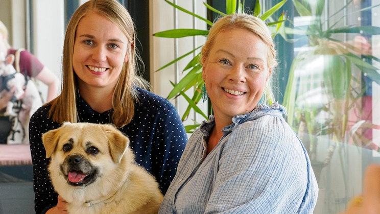 kaksi naista on vierekkäin pitelemässä koiraa