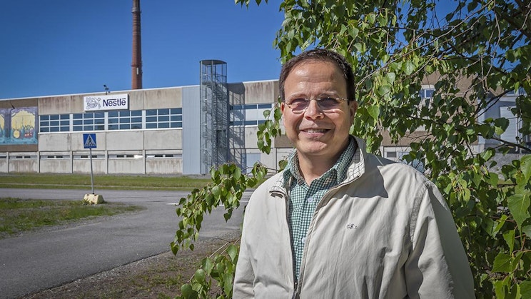 mies seisoo tehdasrakennuksen edessä