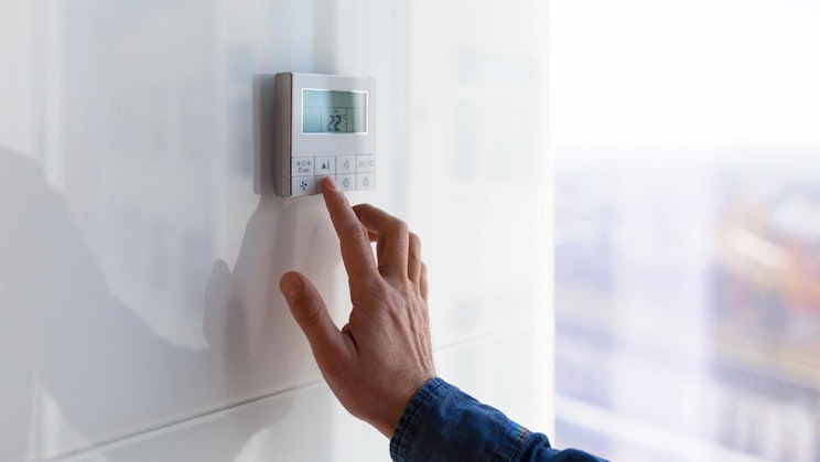 henkilö painaa painiketta valkoisella seinällä