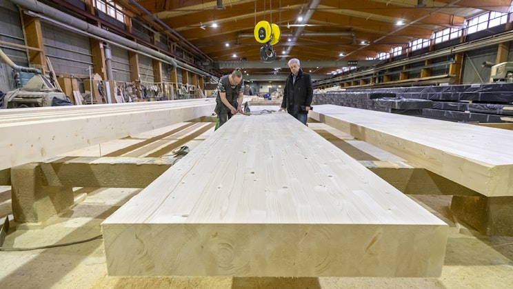 Liimapuupalkki, jonka ääressä kaksi ihmistä.