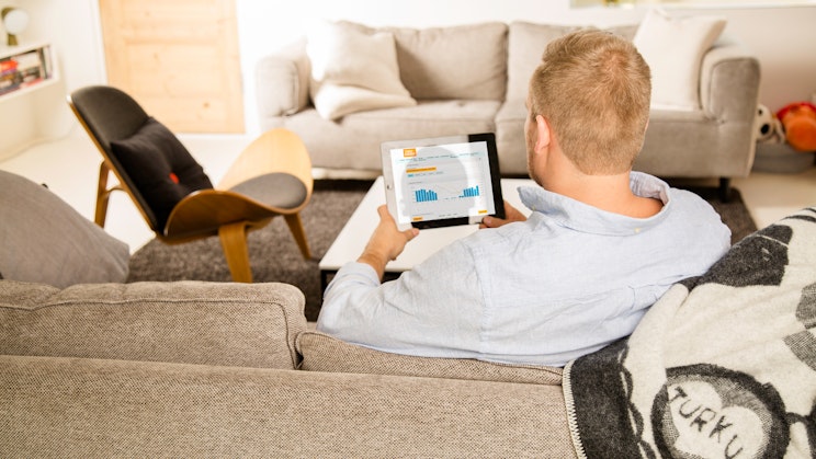 Ihminen sohvalla katsomassa tabletilta graafia.