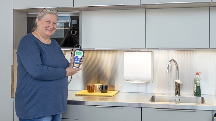 nainen seisoo keittiössä kädessään kännykkä