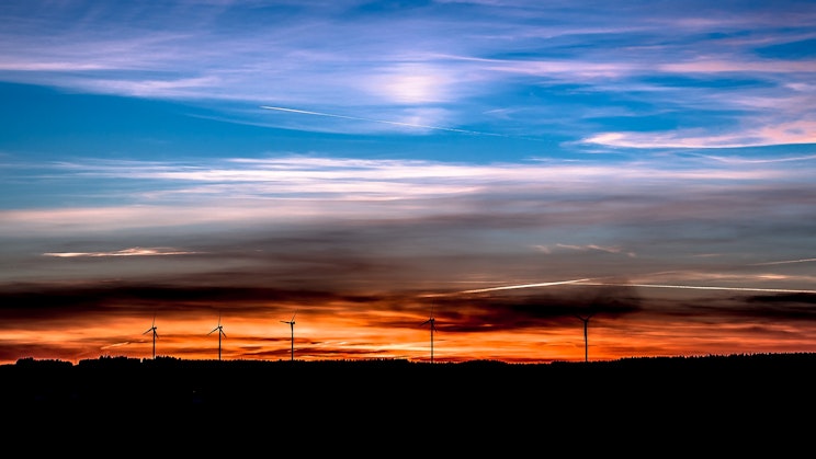 Ryhmä tuuliturbiineita auringonlaskun edustalla.