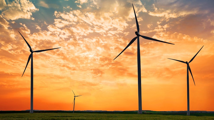 4 tuulimyllyjä pellolla auringonlaskun aikaan.