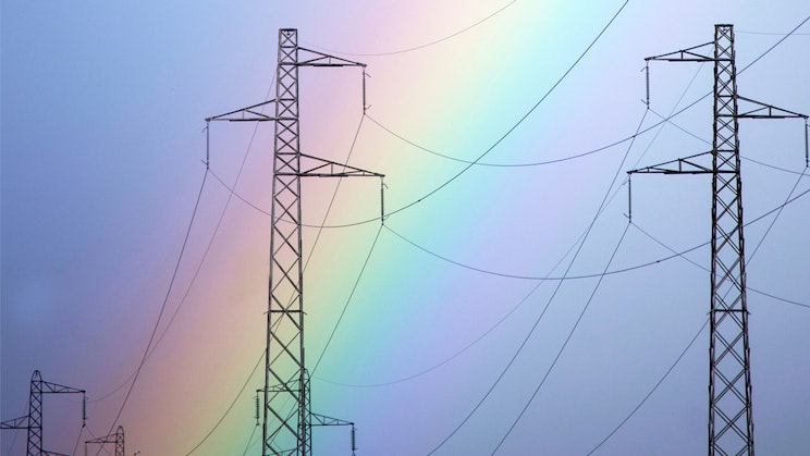 Joukko sähkölinjoja, joiden taustalla on sateenkaari.