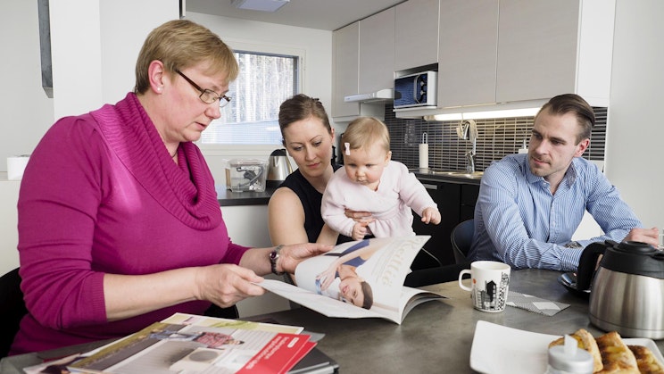 mies, nainen ja vauva istuvat keittiön pöydän ääressä