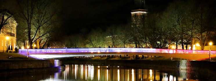 silta joen yli yöllä kellotornin taustalla